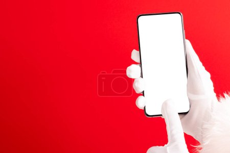 Photo for Santa claus hands holding smartphone with copy space on red background. Christmas, decorations, tradition and celebration concept. - Royalty Free Image
