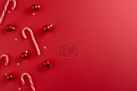 Foto de Adornos de adornos de adornos navideños y bastones de caramelo con espacio para copiar sobre fondo rojo. Navidad, decoraciones, tradición y concepto de celebración. - Imagen libre de derechos