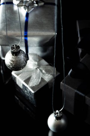 Téléchargez les photos : Image verticale de boules de Noël en argent et cadeaux avec espace de copie sur fond noir. Noël, décorations, concept de tradition et de célébration. - en image libre de droit