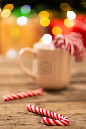 Foto de Imagen vertical de taza con bastones de caramelo y árbol de Navidad con luces de hadas y espacio de copia. Navidad, tradición y concepto de celebración. - Imagen libre de derechos