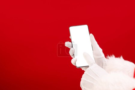 Foto de Santa Claus sosteniendo smattphone con espacio de copia sobre fondo rojo. Santa Claus, tecnología, navidad, tradición y concepto de celebración. - Imagen libre de derechos