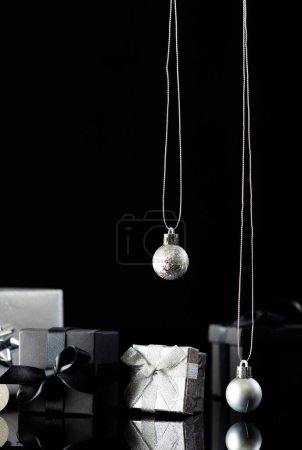 Téléchargez les photos : Image verticale de boules de Noël en argent et cadeaux avec espace de copie sur fond noir. Noël, décorations, concept de tradition et de célébration. - en image libre de droit
