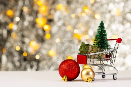 Photo for Shopping trolley with christmas decorations and christmas fairy lights with copy space background. Christmas, decorations, tradition and celebration concept. - Royalty Free Image