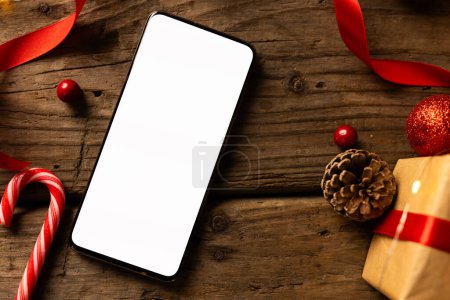 Téléchargez les photos : Smartphone avec espace de copie et décorations de Noël sur fond en bois. Noël, décorations, concept de tradition et de célébration. - en image libre de droit