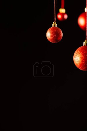 Photo for Vertical image of red christmas baubles with copy space on black background. Christmas, decorations, tradition and celebration concept. - Royalty Free Image