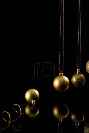 Téléchargez les photos : Image verticale de boules de Noël en or avec espace de copie sur fond noir. Noël, décorations, concept de tradition et de célébration. - en image libre de droit