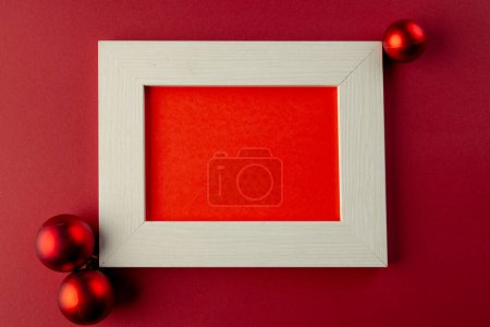 Photo for Red baubles christmas decorations and wooden frame with copy space on red background. Christmas, decorations, tradition and celebration concept. - Royalty Free Image