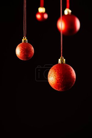 Foto de Imagen vertical de adornos rojos de navidad con espacio de copia sobre fondo negro. Navidad, decoraciones, tradición y concepto de celebración. - Imagen libre de derechos