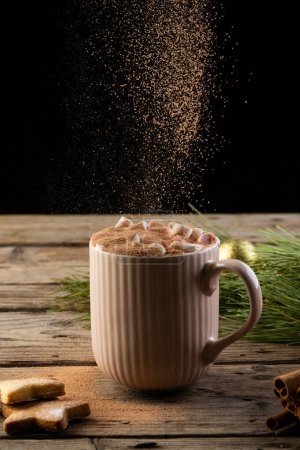 Photo for Vertical image of chocolate pouring over mug of chocolate and christmas decorations with copy space. Christmas, tradition and celebration concept. - Royalty Free Image
