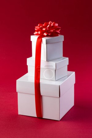 Téléchargez les photos : Image verticale de la pile de cadeaux de Noël avec ruban rouge et espace de copie sur fond rouge. Cadeaux, Noël, concept de tradition et de célébration. - en image libre de droit
