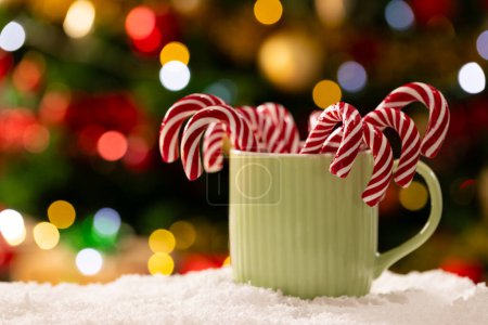 Foto de Taza con bastones de caramelo y árbol de Navidad con luces de hadas y espacio de copia. Navidad, tradición y concepto de celebración. - Imagen libre de derechos