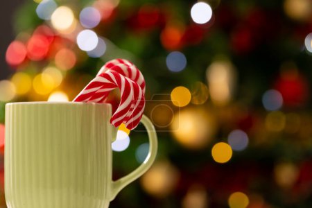 Téléchargez les photos : Tasse avec des cannes à bonbons et un arbre de Noël avec des lumières de fées et de l'espace de copie. Noel, tradition et concept de célébration. - en image libre de droit