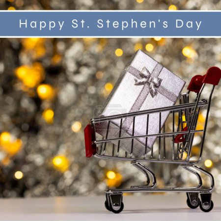 Photo for Composite of happy st stephen's day text and gift box in shopping cart over christmas decorations. Saint, christian martyr, honor, commemorates, holiday, discount, sale, present, celebration. - Royalty Free Image