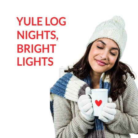 Photo for Yule log nights, bright lights text and biracial woman in warm clothes with heart mug at christmas. Celebration of winter, seasonal greeting and christmas traditions, digitally generated image. - Royalty Free Image