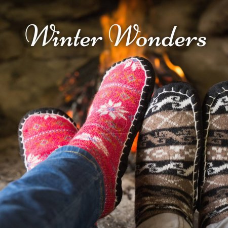 Photo for Composite of winter wonders text over man and woman's feet in christmas socks by fireplace. Winter, christmas, seasons and celebration concept digitally generated image. - Royalty Free Image