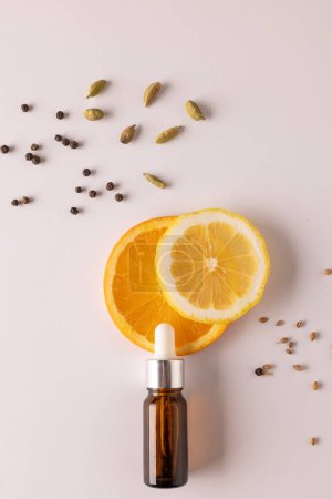 Foto de Imagen vertical de botella con pipeta y naranjas y semillas con espacio de copia sobre fondo blanco. Salud y belleza, producto de belleza, maquillaje y concepto de color. - Imagen libre de derechos