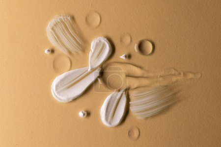 Photo for Close up of beauty product white cream and clear serum smudge with copy space on brown background. Health and beauty, beauty product, make up and colour concept. - Royalty Free Image