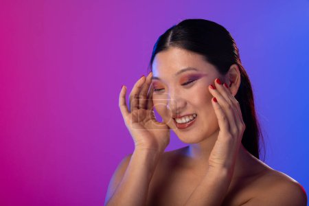 Photo for Asian woman wearing purple eye shadow and red nail polish on purple background, copy space. Cosmetics, makeup, female fashion and beauty, unaltered. - Royalty Free Image
