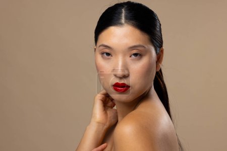 Téléchargez les photos : Portrait de femme asiatique portant rouge à lèvres et vernis à ongles sur fond beige, espace de copie. Cosmétiques, maquillage, mode féminine et beauté, inchangés. - en image libre de droit