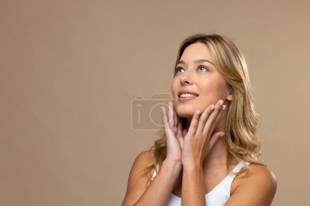 Foto de Mujer caucásica con maquillaje natural y esmalte de uñas beige sobre fondo beige, espacio para copiar. Cosméticos, maquillaje, moda femenina y belleza, inalterados. - Imagen libre de derechos
