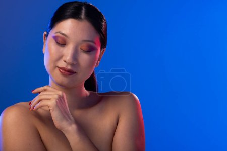 Téléchargez les photos : Femme asiatique portant ombre à paupières violette et vernis à ongles rouge sur fond violet, espace de copie. Cosmétiques, maquillage, mode féminine et beauté, inchangés. - en image libre de droit