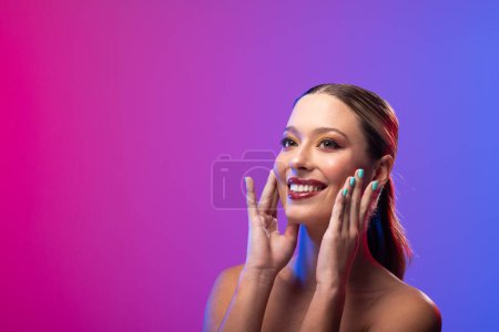 Foto de Mujer caucásica con lápiz labial rojo y esmalte de uñas azul sobre fondo púrpura, espacio para copiar. Cosméticos, maquillaje, moda femenina y belleza, inalterados. - Imagen libre de derechos