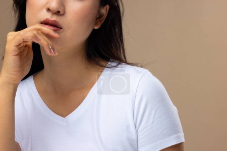 Foto de Mujer asiática con maquillaje natural y camiseta blanca sobre fondo beige. Cosméticos, maquillaje, moda femenina y belleza, inalterados. - Imagen libre de derechos