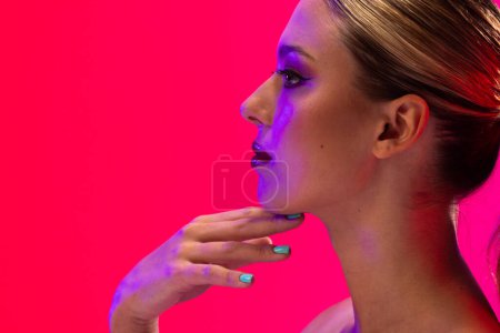 Foto de Mujer caucásica con lápiz labial rojo y esmalte de uñas azul sobre fondo rosa, espacio para copiar. Cosméticos, maquillaje, moda femenina y belleza, inalterados. - Imagen libre de derechos