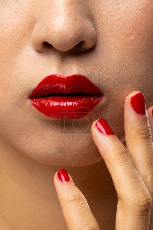Foto de Primer plano de la mujer asiática con lápiz labial rojo y esmalte de uñas. Cosméticos, maquillaje, moda femenina y belleza, inalterados. - Imagen libre de derechos