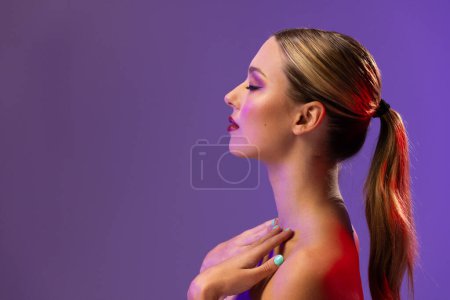Foto de Mujer caucásica con lápiz labial rojo y esmalte de uñas azul sobre fondo púrpura, espacio para copiar. Cosméticos, maquillaje, moda femenina y belleza, inalterados. - Imagen libre de derechos