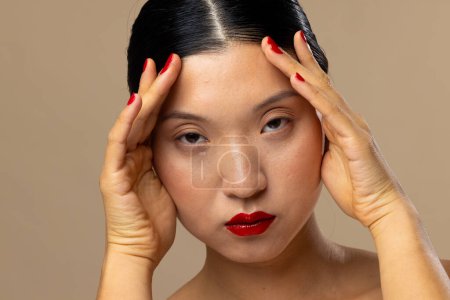 Téléchargez les photos : Portrait de femme asiatique portant rouge à lèvres et vernis à ongles sur fond beige. Cosmétiques, maquillage, mode féminine et beauté, inchangés. - en image libre de droit