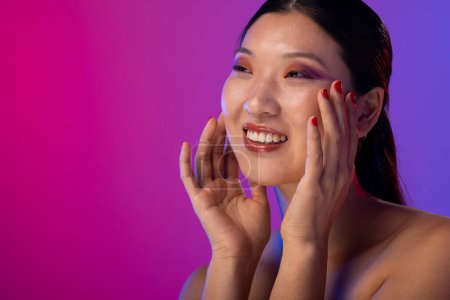 Photo for Asian woman wearing purple eye shadow and red nail polish on purple background, copy space. Cosmetics, makeup, female fashion and beauty, unaltered. - Royalty Free Image