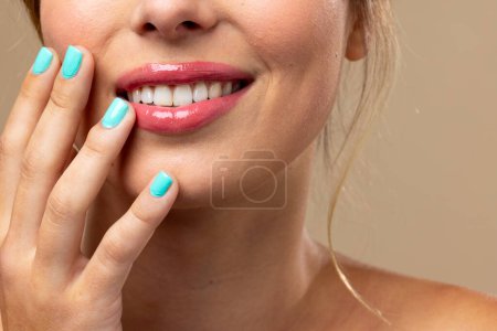 Foto de Mujer caucásica con maquillaje natural y esmalte de uñas azul sobre fondo beige. Cosméticos, maquillaje, moda femenina y belleza, inalterados. - Imagen libre de derechos