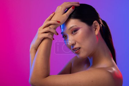 Téléchargez les photos : Portrait de femme asiatique portant ombre à paupières violette et vernis à ongles rouge sur fond violet. Cosmétiques, maquillage, mode féminine et beauté, inchangés. - en image libre de droit