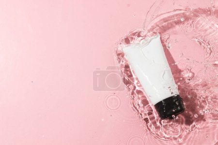 Photo for Beauty product tube in water with copy space background on pink background. Health and beauty, make up and beauty concept. - Royalty Free Image