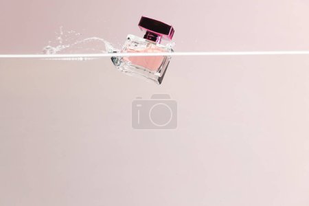 Photo for Beauty product perfume bottle falling into water with copy space background on pink background. Health and beauty, make up and beauty concept. - Royalty Free Image