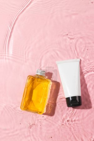 Photo for Vertical image of beauty products in water with copy space background on pink background. Health and beauty, make up and beauty concept. - Royalty Free Image