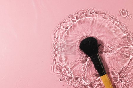 Téléchargez les photos : Produit de beauté maquillage brosse dans l'eau avec un fond d'espace de copie sur fond rose. Santé et beauté, concept maquillage et beauté. - en image libre de droit