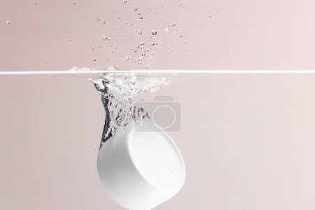 Foto de Bañera de productos de belleza cayendo en el agua con fondo de espacio de copia sobre fondo rosa. Salud y belleza, maquillaje y concepto de belleza. - Imagen libre de derechos