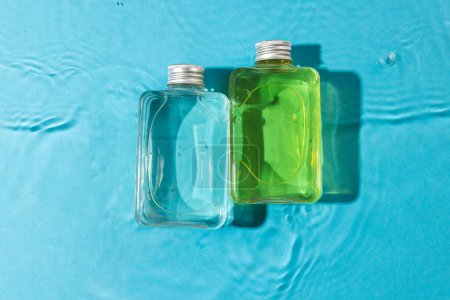 Foto de Botellas de productos de belleza en agua con fondo de espacio de copia sobre fondo azul. Salud y belleza, maquillaje y concepto de belleza. - Imagen libre de derechos