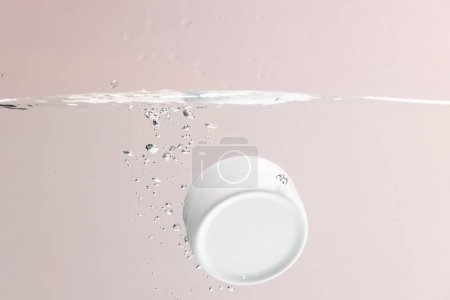 Photo for Beauty product tub falling into water with copy space background on pink background. Health and beauty, make up and beauty concept. - Royalty Free Image