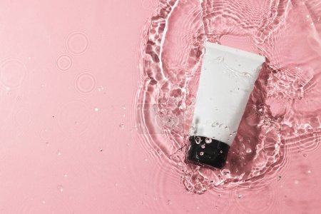 Foto de Tubo de producto de belleza en agua con fondo de espacio de copia sobre fondo rosa. Salud y belleza, maquillaje y concepto de belleza. - Imagen libre de derechos