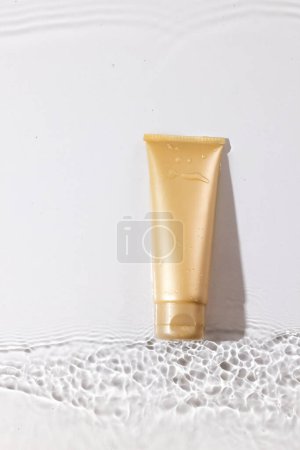 Photo for Vertical image of beauty product tube in water with copy space background on white background. Health and beauty, make up and beauty concept. - Royalty Free Image