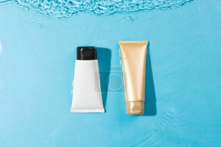 Photo for Beauty product tubes in water with copy space background on blue background. Health and beauty, make up and beauty concept. - Royalty Free Image