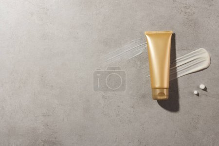 Photo for Beauty product gold tube and cream smudges with copy space on stone background. Health and beauty, make up and beauty concept. - Royalty Free Image