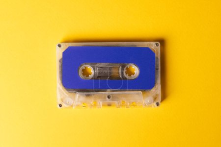 Photo for Overhead view of blue cassette tape on yellow background. Music, sound, listening, entertainment and nostalgia concept. - Royalty Free Image
