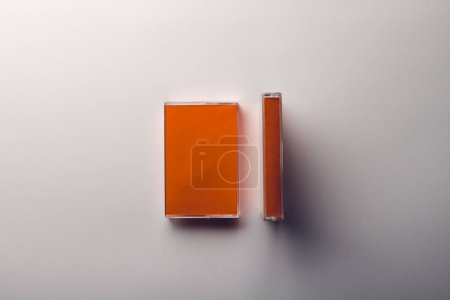 Téléchargez les photos : Vue aérienne de deux cassettes orange avec espace de copie disposé sur fond blanc. Concept de musique, son, écoute, divertissement et nostalgie. - en image libre de droit