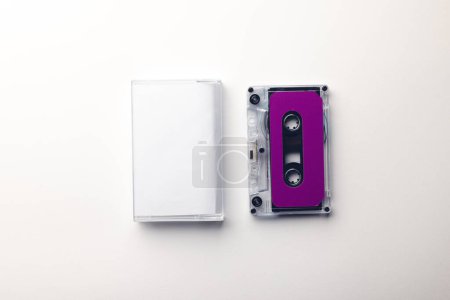 Photo for Overhead view of purple cassette tape and white box arranged on white background. Music, sound, listening, entertainment and nostalgia concept. - Royalty Free Image
