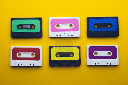 Téléchargez les photos : Vue aérienne de six cassettes colorées disposées sur fond jaune. Concept de musique, son, écoute, divertissement et nostalgie. - en image libre de droit