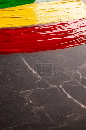 Photo for Vertical image of green, yellow and red paints with copy space on black stone background. Black history month, africa, black culture and history concept. - Royalty Free Image
